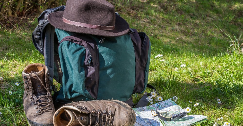 Natur erleben mit Wanderrucksack, Wanderschuhen und Wanderkarte auf grüner Wiese